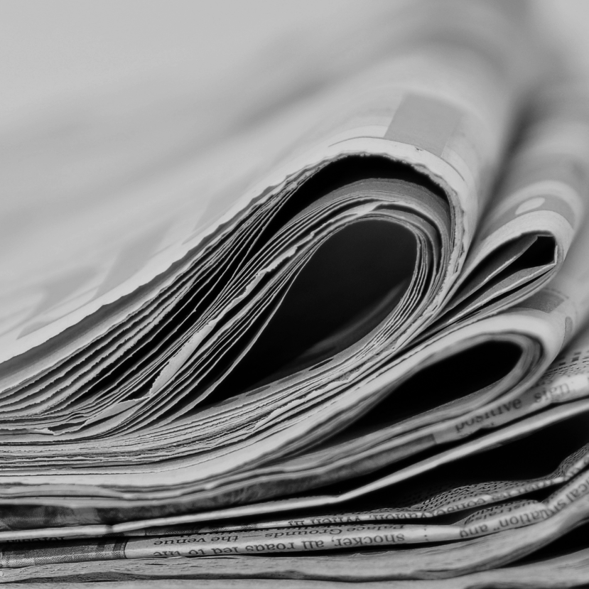 Stack of folded newspapers with visible pages and textures.