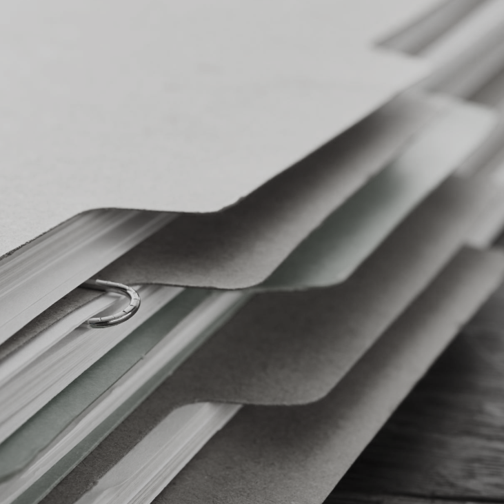 Stack of grey file folders with visible tabs and clear sleeves.