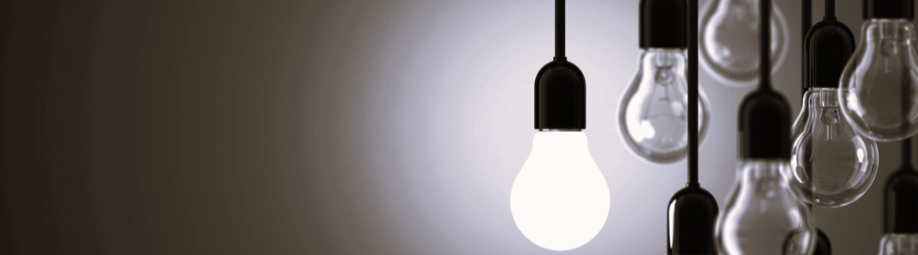 A single glowing lightbulb among several dimmer ones against a grey background.